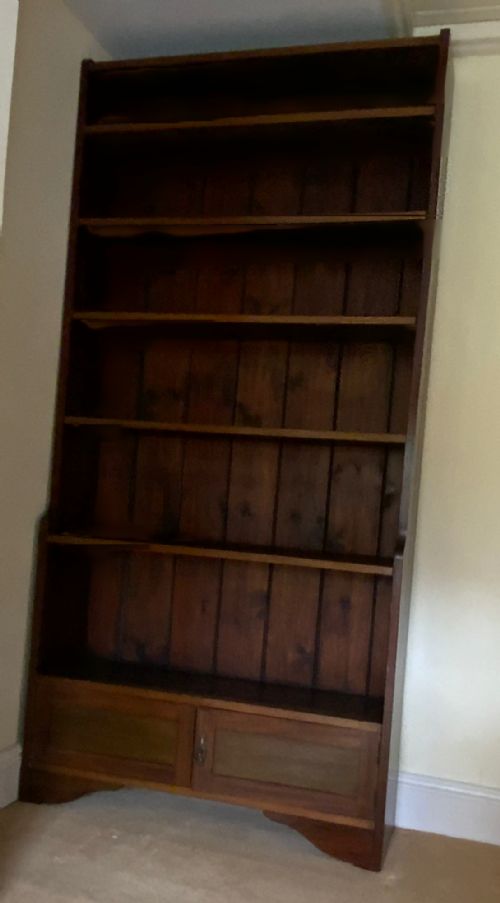 fig 1. A tall antique dark mahogany open bookcase featuring multiple exposed shelves above a two-door base cupboard.