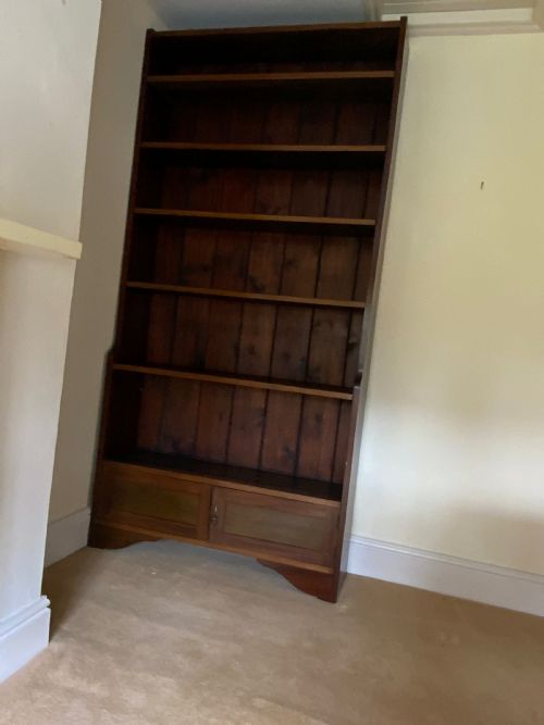 fig 2. A tall antique dark mahogany open bookcase featuring multiple exposed shelves above a two-door base cupboard.