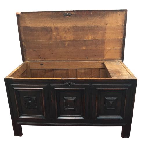 fig 1. A dark oak 17th-century coffer with a rectangular hinged lid and three geometric panelled sections on the front facade.