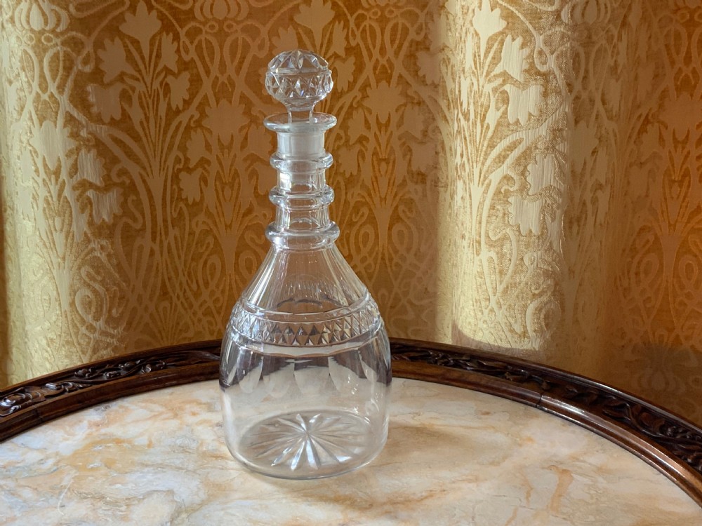 A clear Georgian cut glass decanter featuring three neck rings, a diamond cut band, and a matching mushroom-shaped faceted stopper.