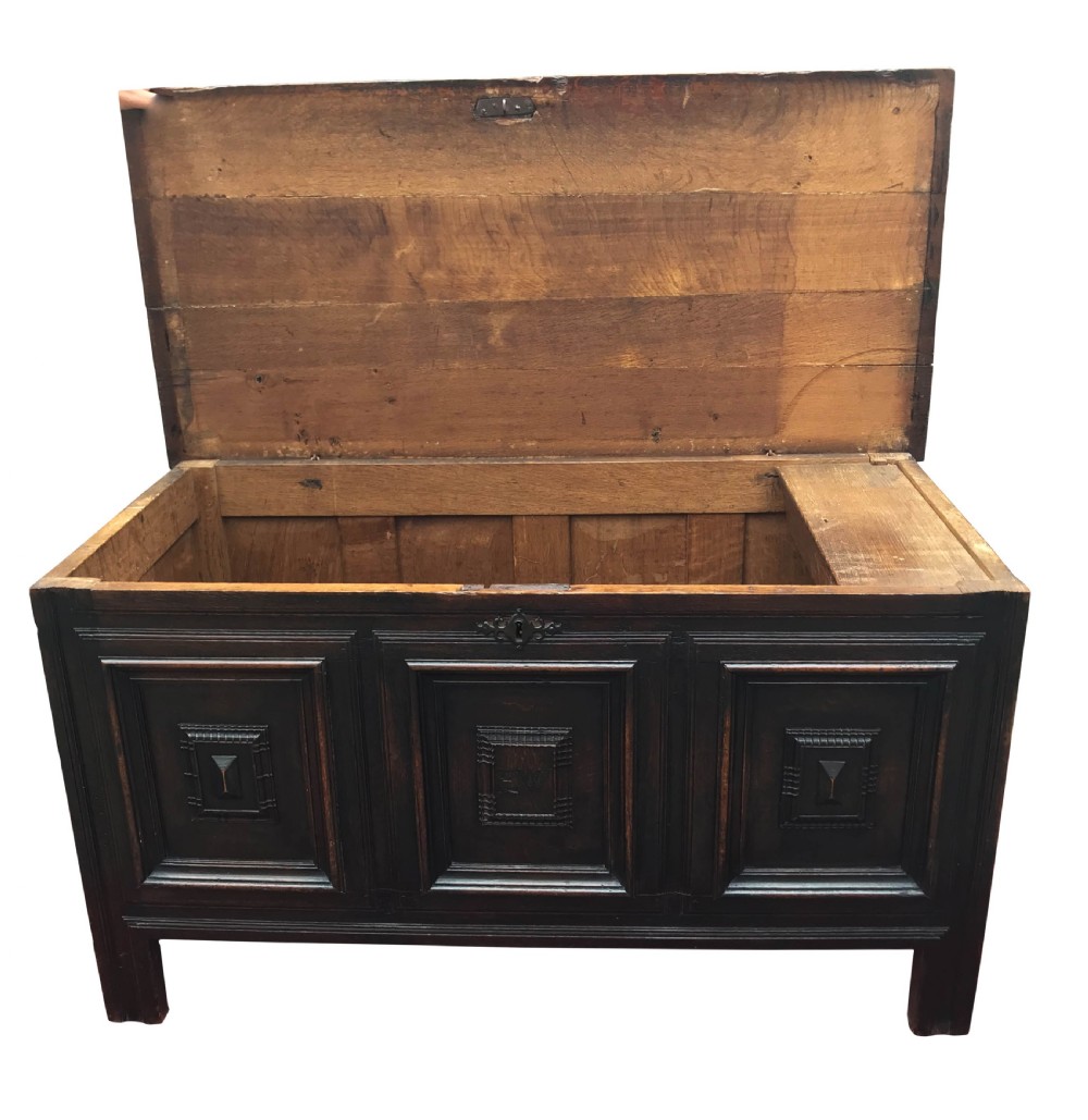A dark oak 17th-century coffer with a rectangular hinged lid and three geometric panelled sections on the front facade. View II