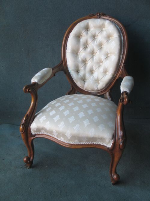 AN OVAL WALNUT BUTTONED BACK ARMCHAIR