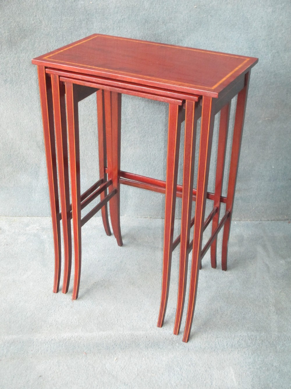 A set of three graduated mahogany nesting tables featuring satinwood stringing inlay along the tops and slender, slightly splayed legs. View II