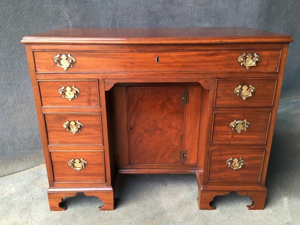 A Georgian style mahogany kneehole desk featuring a flat top, seven pedestal drawers with brass handles, a central recessed cupboard, and bracket feet. View II