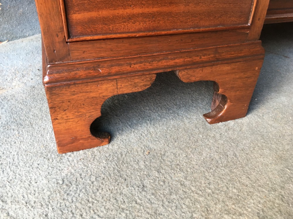 A Georgian style mahogany kneehole desk featuring a flat top, seven pedestal drawers with brass handles, a central recessed cupboard, and bracket feet. View IV