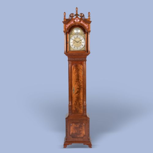 fig 1. A miniature mahogany longcase clock featuring a brass dial, swan-neck pediment with brass finials, and a flame mahogany veneer trunk door.