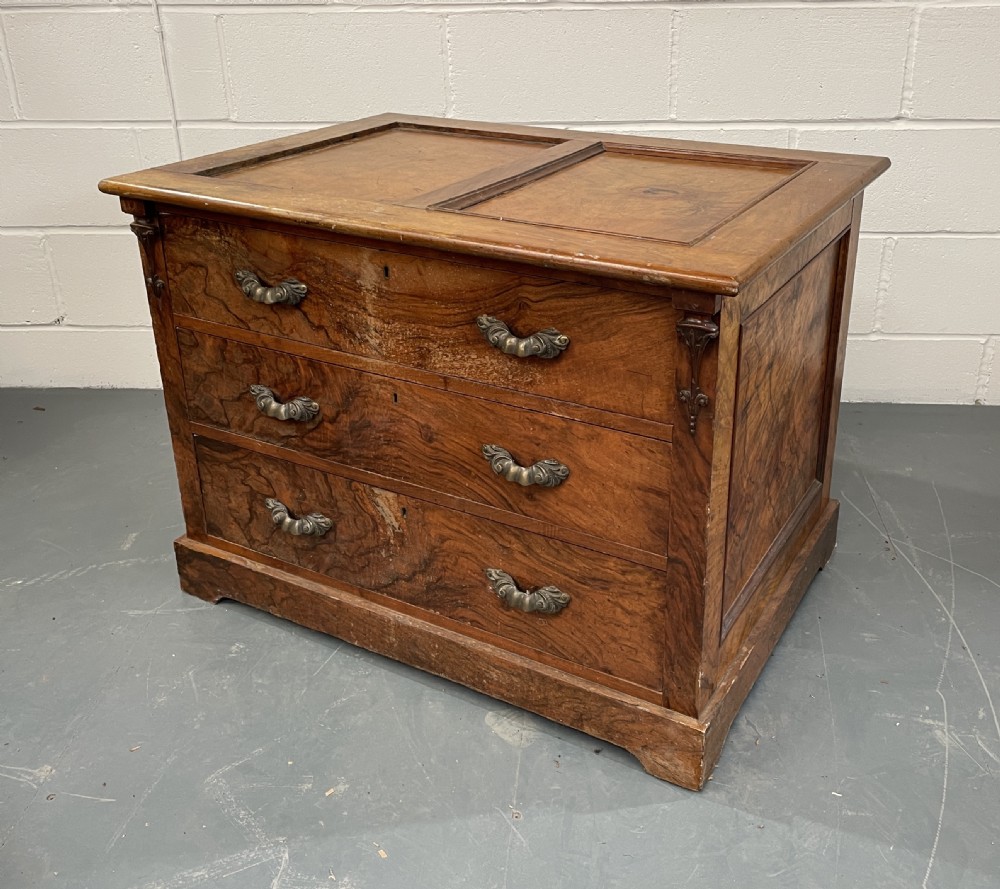 A low antique walnut chest of drawers featuring three full-width drawers with decorative cast metal handles and a panelled top.