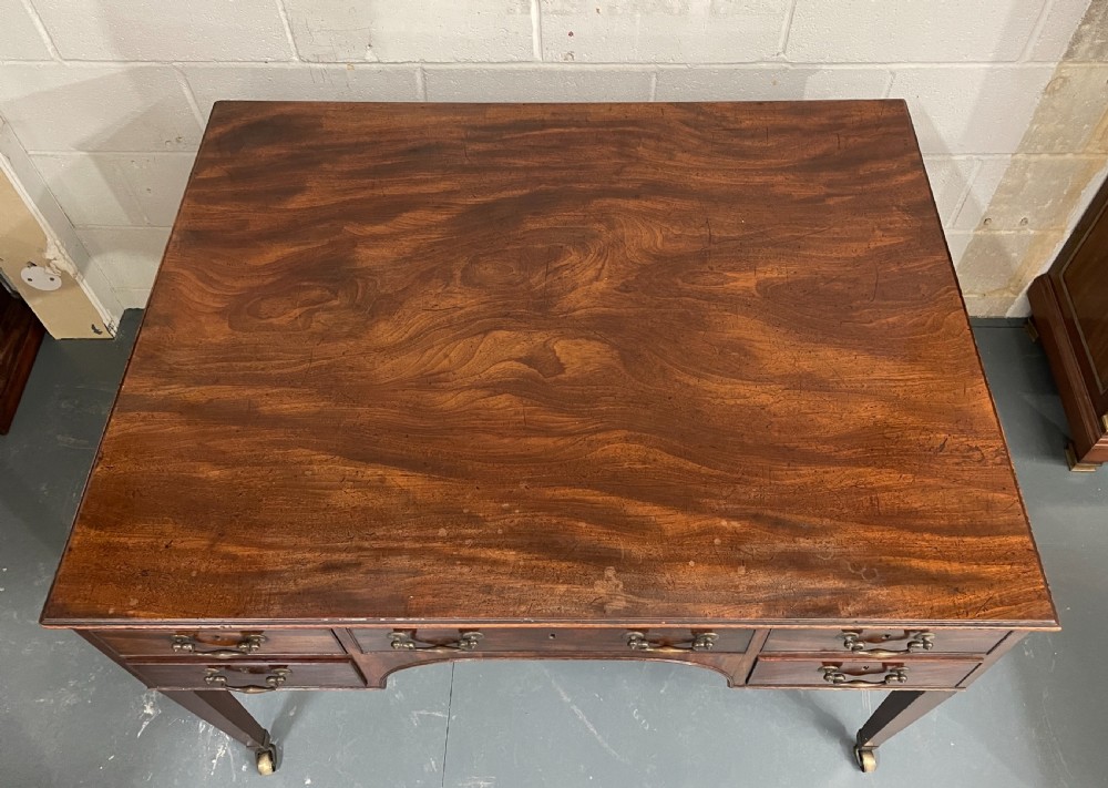 A Georgian mahogany partners writing table featuring multiple drawers with brass drop handles, side carrying handles, and tapered legs on brass castors. View III