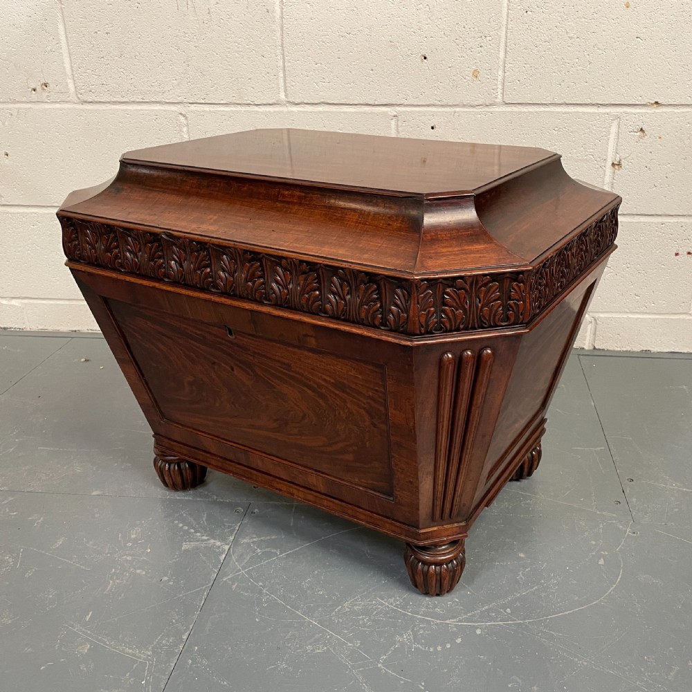 A late Georgian mahogany sarcophagus-form wine cooler featuring carved acanthus detailing, reeded corners, and turned gadrooned feet.