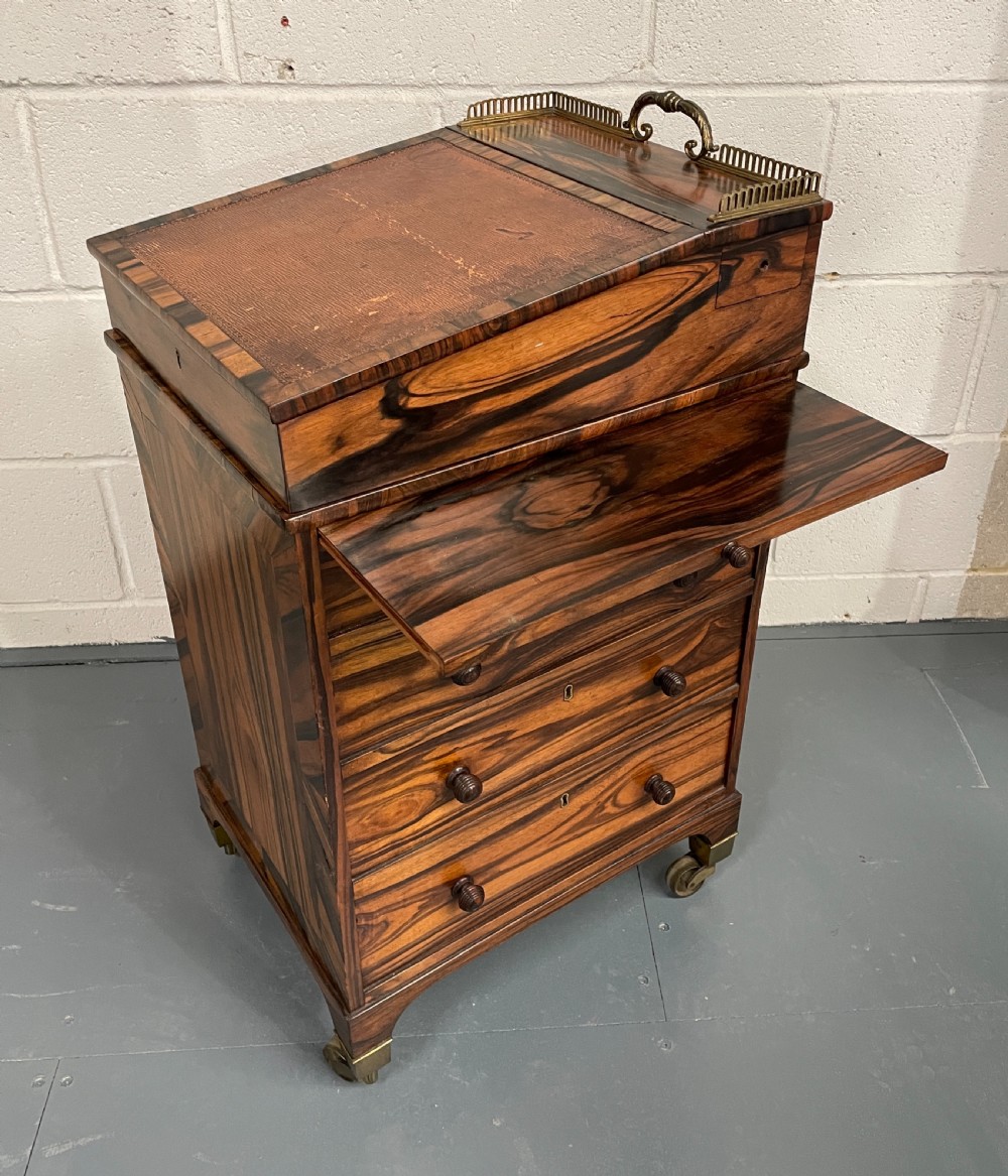A Regency period coromandel Davenport desk featuring a slanted leather inset writing top, top brass gallery, turned wood knobs, and side drawers on brass castors. View II