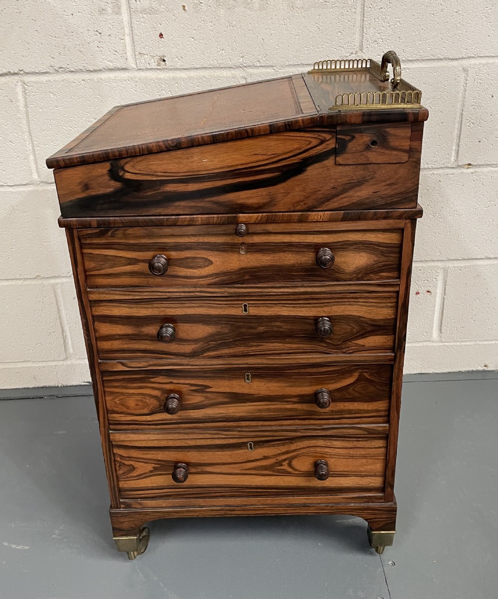 A Regency period coromandel Davenport desk featuring a slanted leather inset writing top, top brass gallery, turned wood knobs, and side drawers on brass castors. View IV