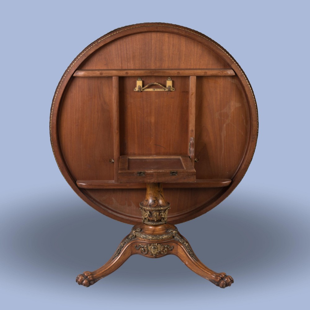 A circular Victorian burr walnut centre table featuring inlaid marquetry cartouches along the border and a carved pedestal base. View V