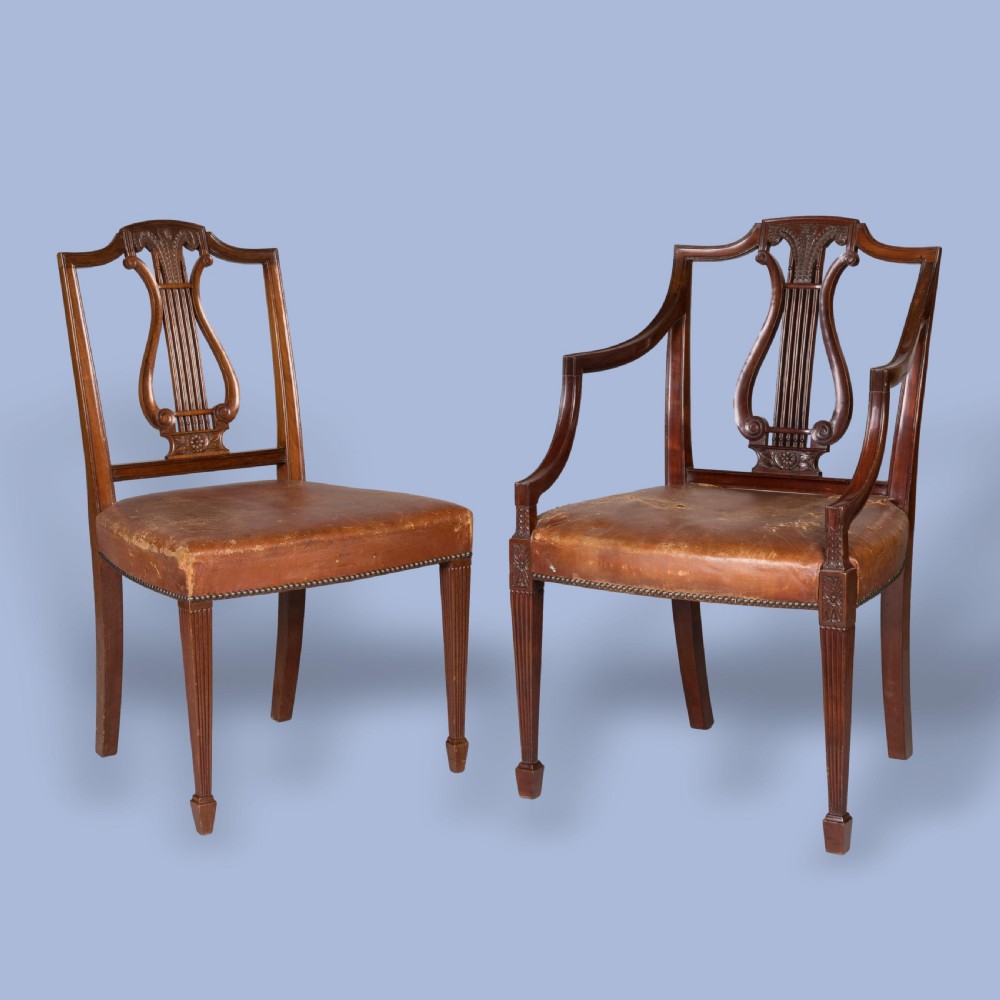 A set of ten carved mahogany dining chairs featuring lyre backs, brown leather upholstered seats with stud trim, and fluted legs. View II