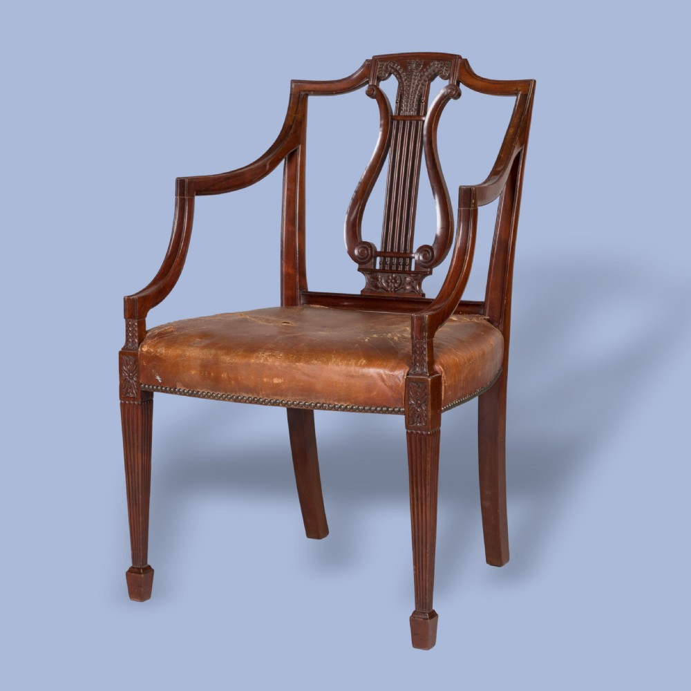 A set of ten carved mahogany dining chairs featuring lyre backs, brown leather upholstered seats with stud trim, and fluted legs. View III