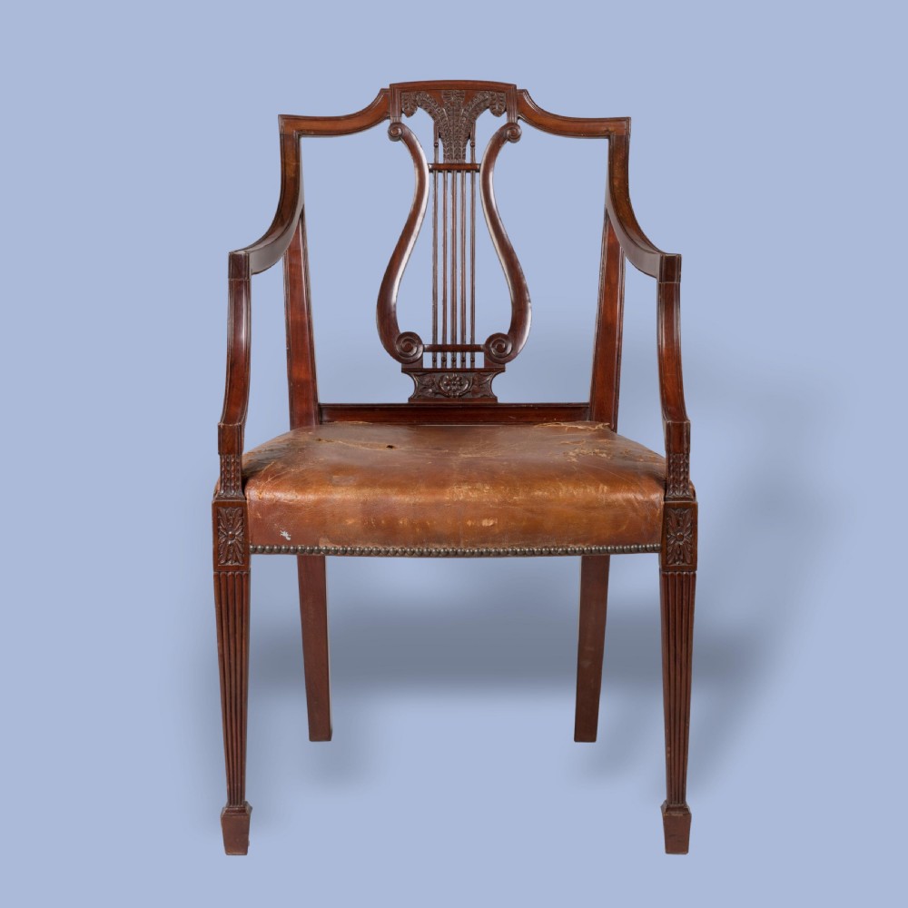 A set of ten carved mahogany dining chairs featuring lyre backs, brown leather upholstered seats with stud trim, and fluted legs. View IV