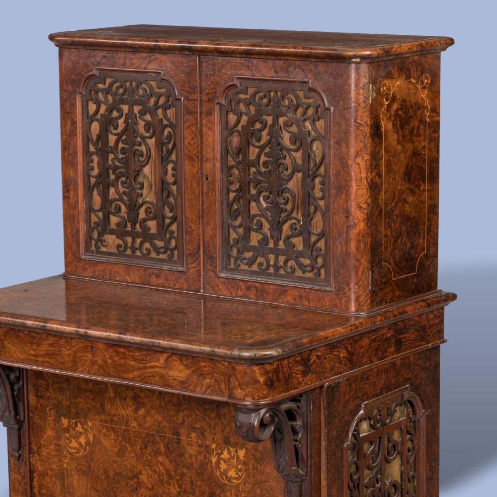 A mid-nineteenth-century Victorian burr walnut Davenport desk featuring pierced fretwork cabinet doors, floral marquetry inlay, carved scroll brackets, and ceramic castors. View II