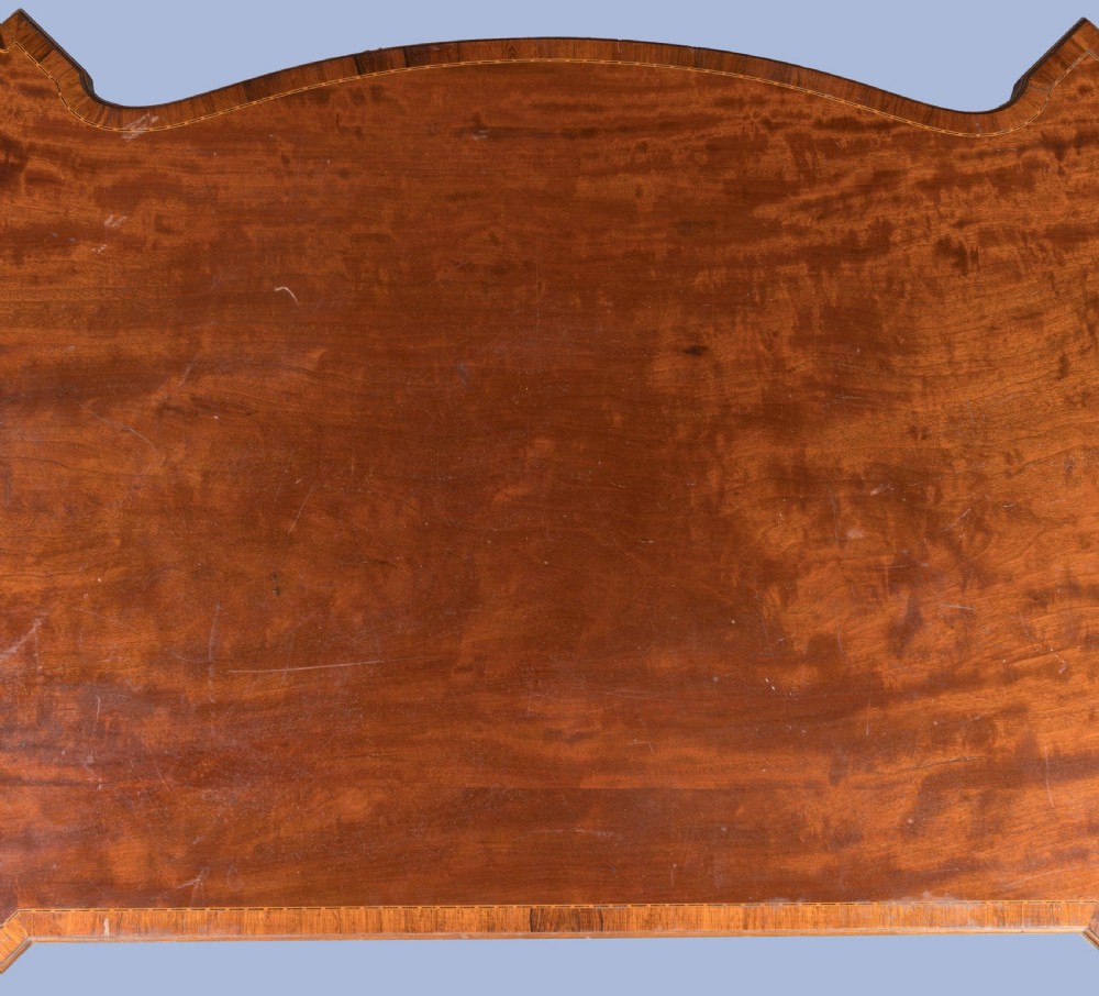 An antique mahogany pedestal desk featuring a serpentine front, parquetry drawer fronts, brass handles, and carved blind fretwork along the frieze. View VII
