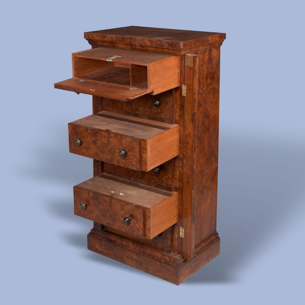 A tall, narrow Victorian Wellington chest of drawers featuring six drawers crafted from highly figured warm brown timber with carved side stiles and turned wooden knob handles. View III