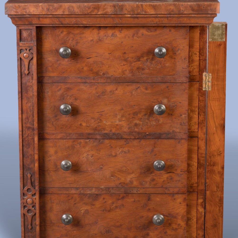 A tall, narrow Victorian Wellington chest of drawers featuring six drawers crafted from highly figured warm brown timber with carved side stiles and turned wooden knob handles. View V