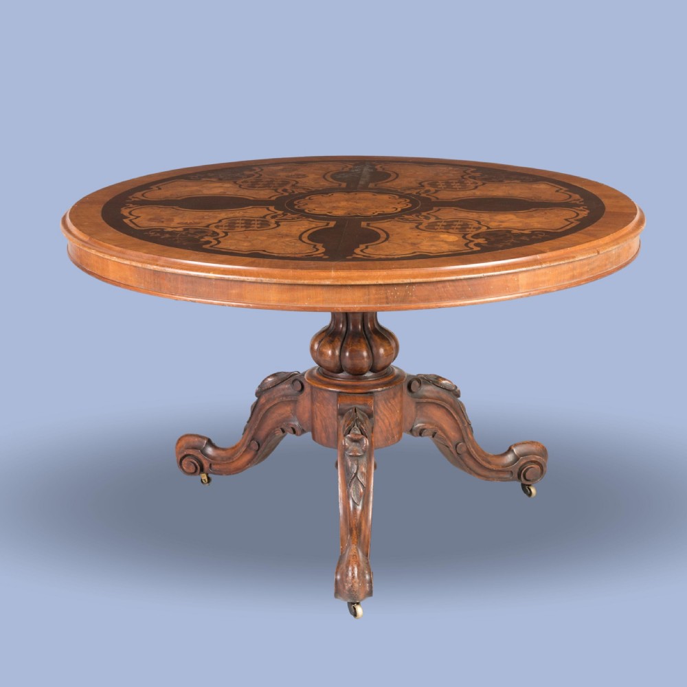 A circular Victorian walnut centre table featuring elaborate floral marquetry inlay set on a carved tripod base. View II