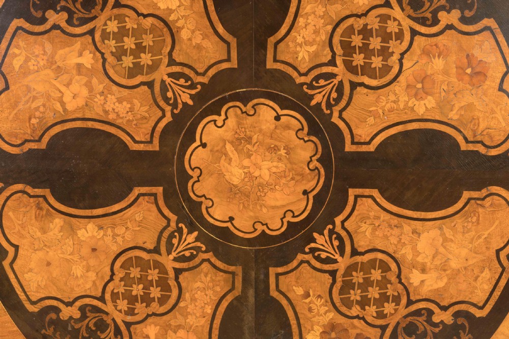 A circular Victorian walnut centre table featuring elaborate floral marquetry inlay set on a carved tripod base. View IV