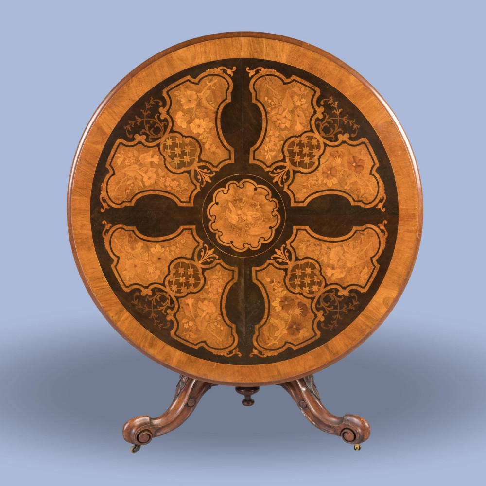 A circular Victorian walnut centre table featuring elaborate floral marquetry inlay set on a carved tripod base.