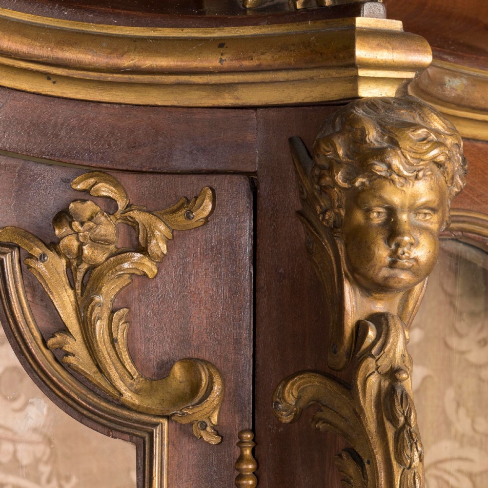 A French Transitional style bombe vitrine featuring curved glazed sides, floral marquetry panels, cabriole legs, and ornate gilt-bronze mounts. View III