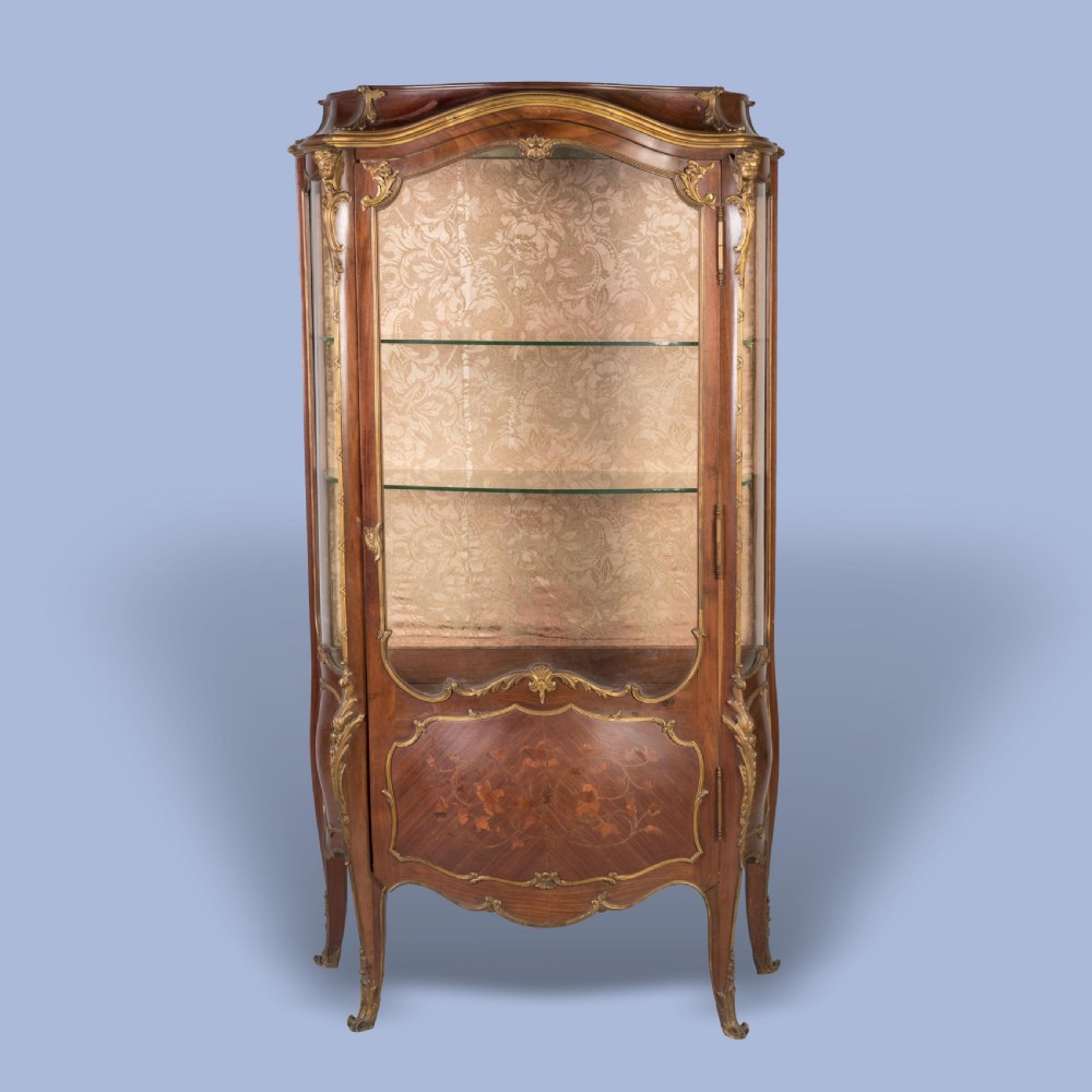 A French Transitional style bombe vitrine featuring curved glazed sides, floral marquetry panels, cabriole legs, and ornate gilt-bronze mounts. View VI