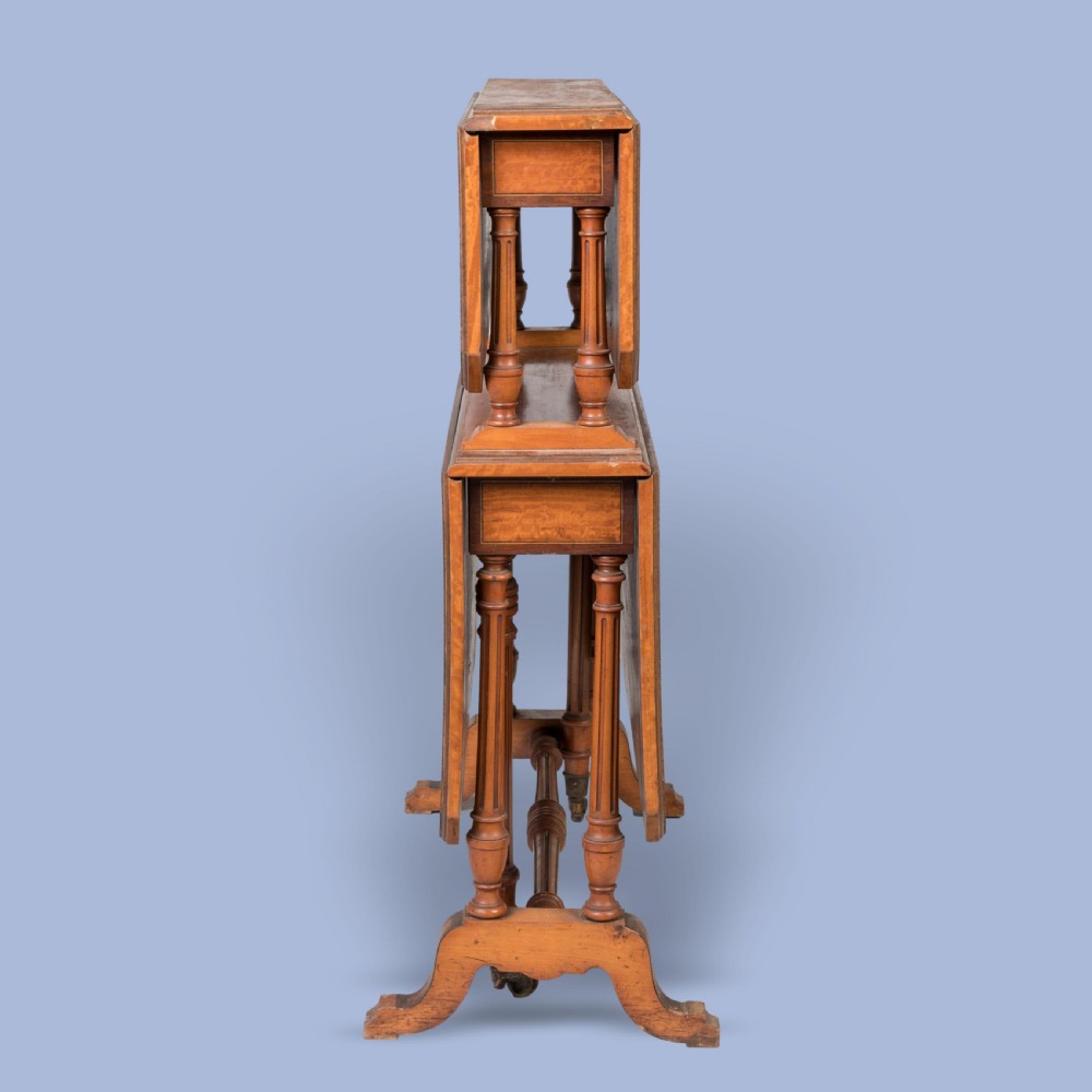 A double-tiered satinwood Sutherland drop-leaf table featuring turned leg supports, crossbanded borders, and brass castors. View IV