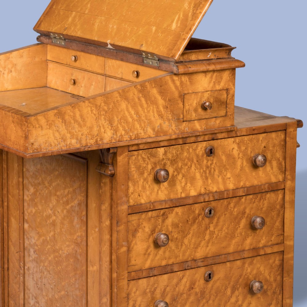 A late Georgian davenport desk crafted from golden timber with a sliding slanted leather writing top, side drawers with turned wooden knobs, and an extended side pen drawer. View III