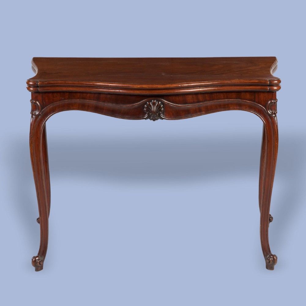 A Georgian mahogany fold-over card table featuring slender cabriole legs, a carved shell central apron motif, and a serpentine front.