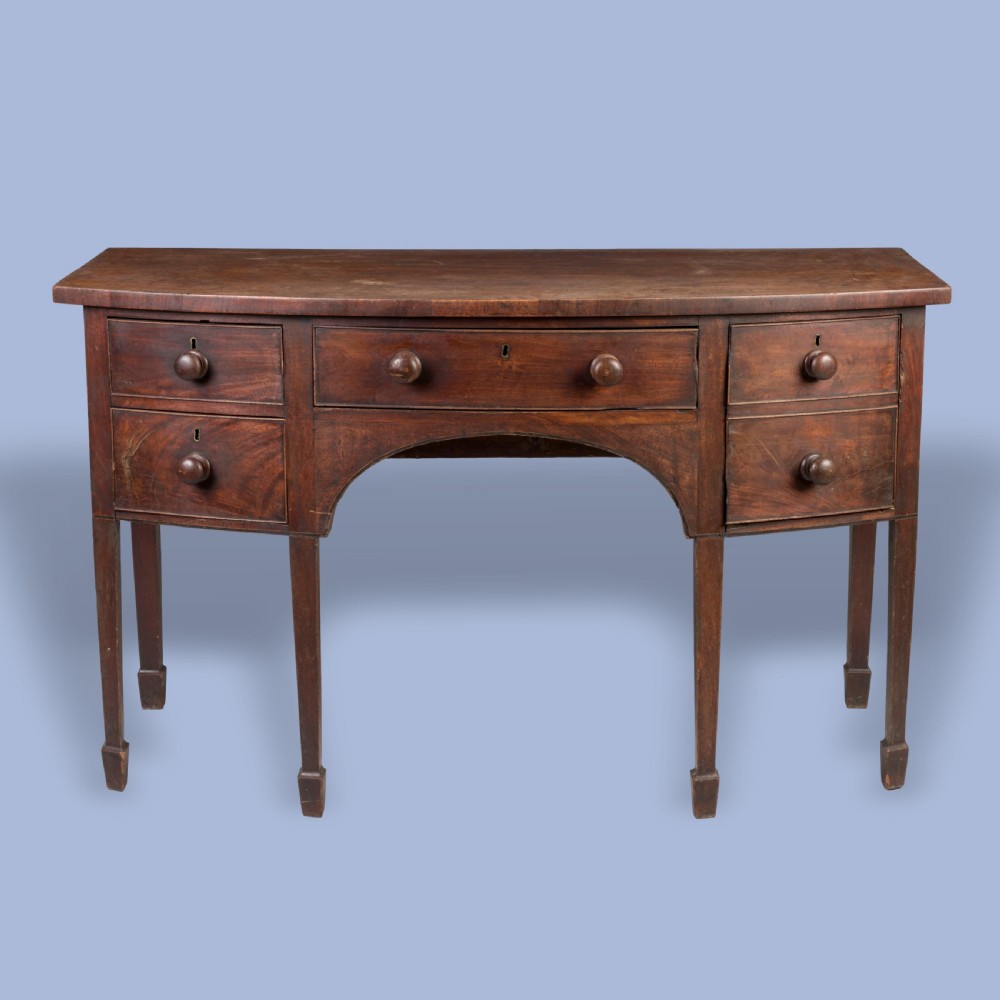 A Georgian mahogany bowfront sideboard featuring a central drawer flanked by side drawers, supported on square tapered legs with spade feet.