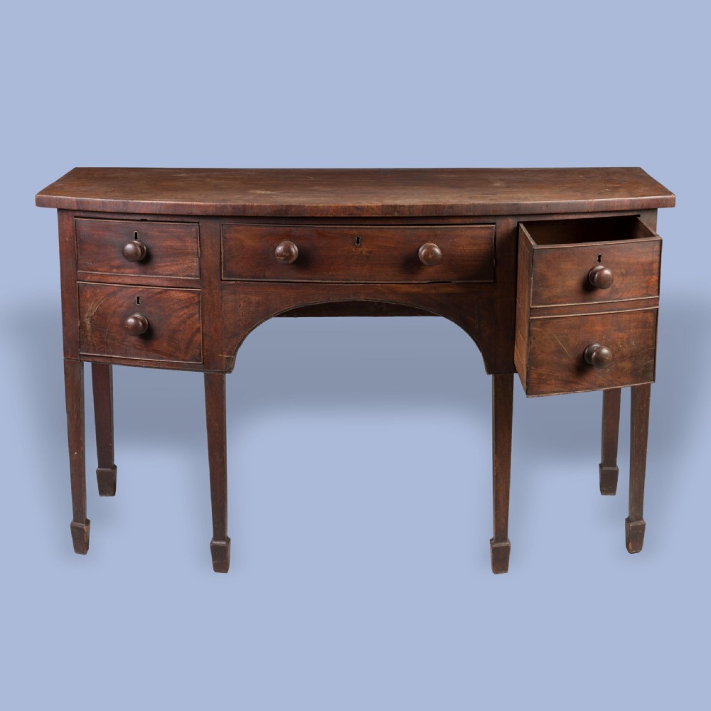 A Georgian mahogany bowfront sideboard featuring a central drawer flanked by side drawers, supported on square tapered legs with spade feet. View V