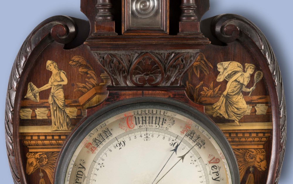 A wall-mounted Neo-Classical mahogany barometer featuring detailed marquetry inlay of classical figures, an upper thermometer tube, and a central circular dial. View IV