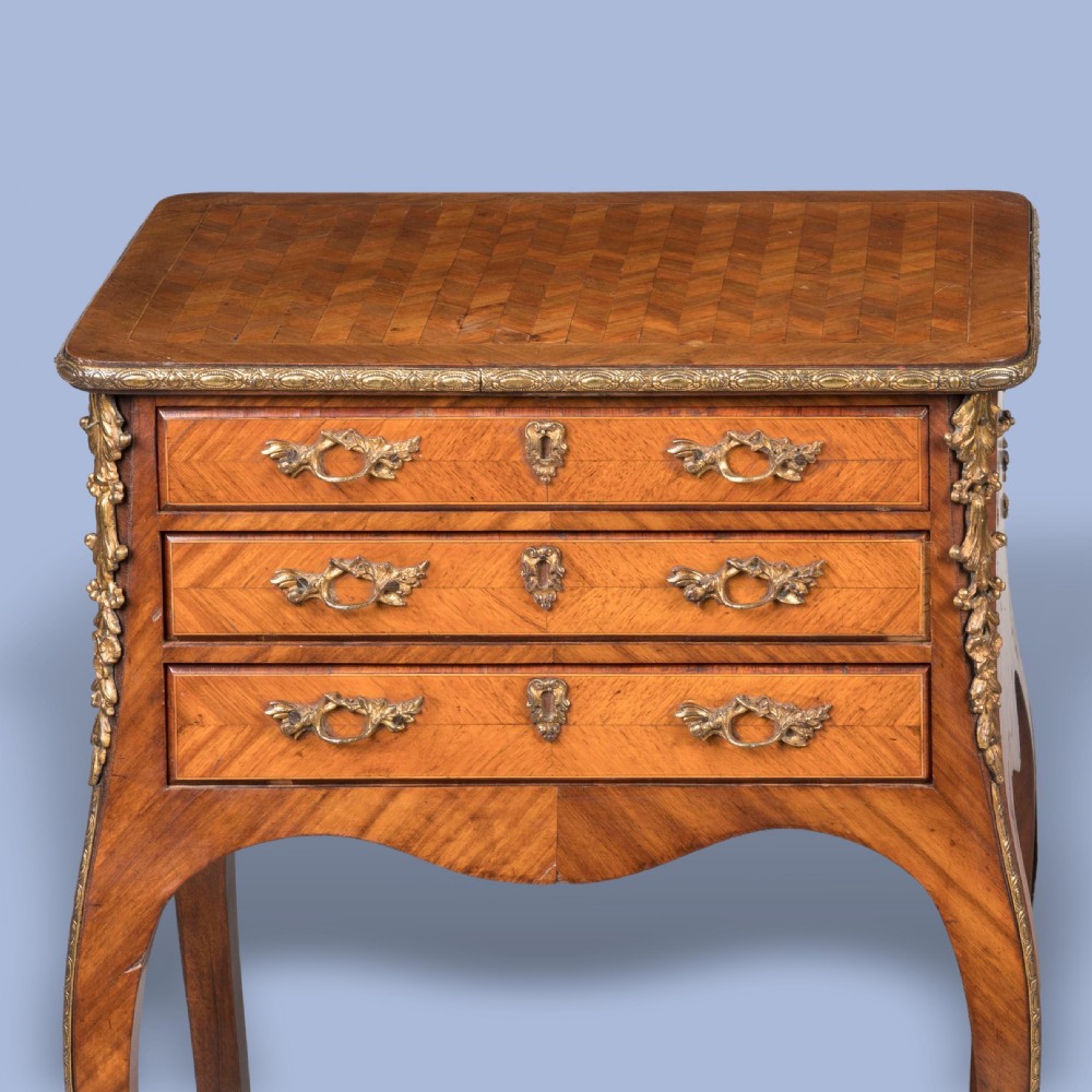 A matched pair of French Louis XV style wooden bedside tables featuring geometric parquetry veneer, three drawers, gilt bronze mounts, and slender cabriole legs. View II