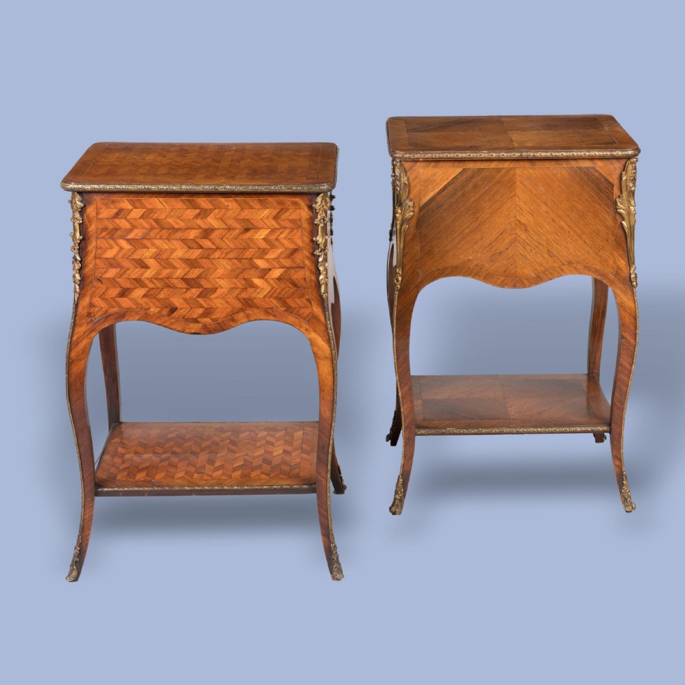 A matched pair of French Louis XV style wooden bedside tables featuring geometric parquetry veneer, three drawers, gilt bronze mounts, and slender cabriole legs. View IV