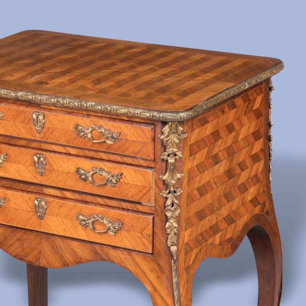 A matched pair of French Louis XV style wooden bedside tables featuring geometric parquetry veneer, three drawers, gilt bronze mounts, and slender cabriole legs. View VI
