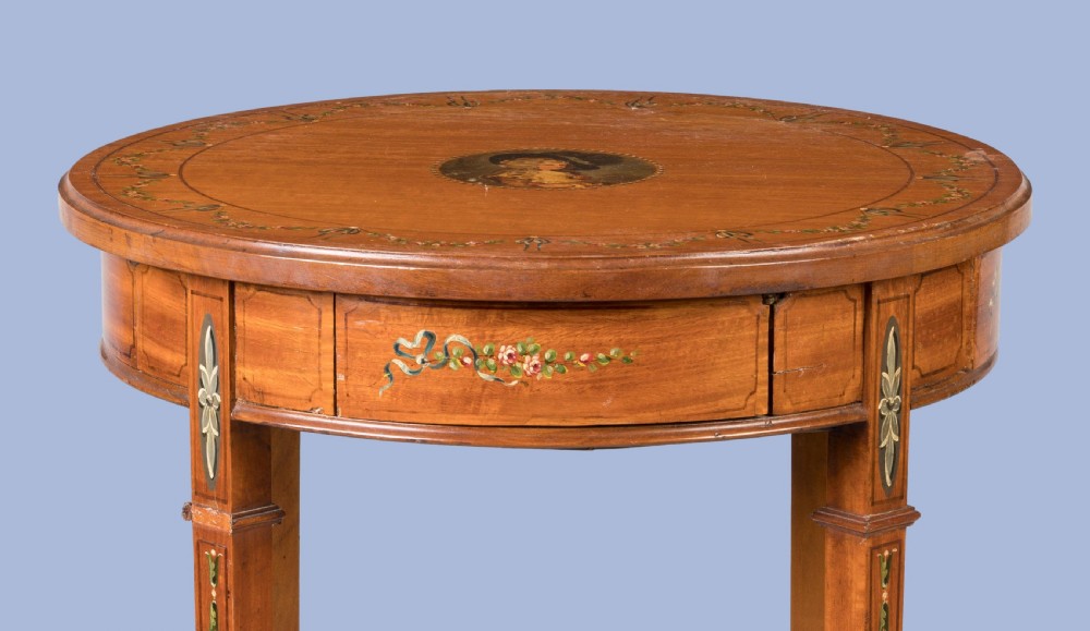 A round satinwood occasional table featuring hand-painted floral swags, tapered square legs, and a raised central stretcher. View VI