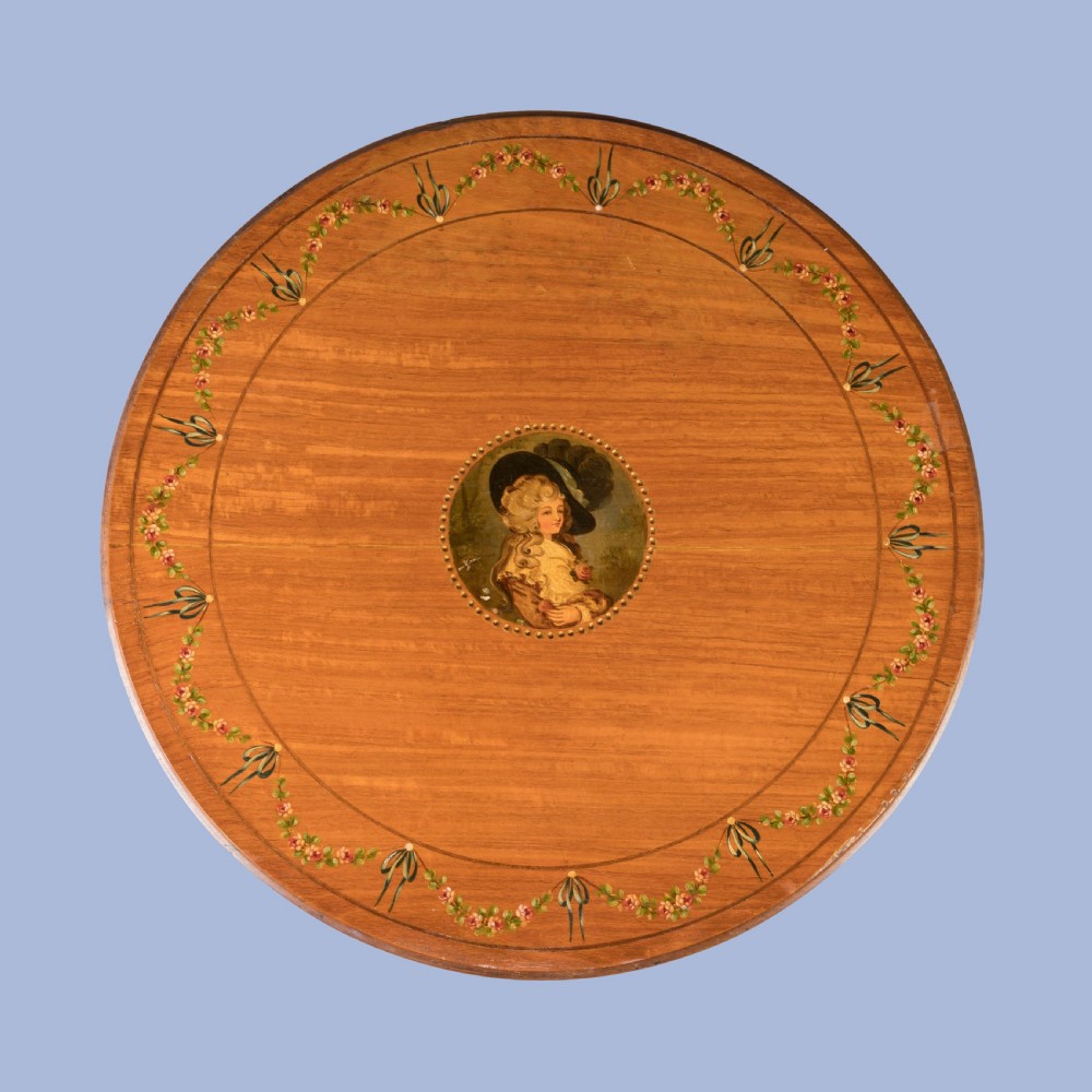 A round satinwood occasional table featuring hand-painted floral swags, tapered square legs, and a raised central stretcher. View VII