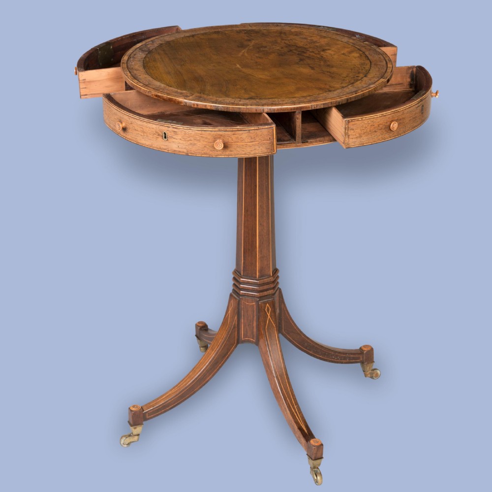 A small Regency mahogany drum table featuring a circular top with frieze drawers, supported on an inlaid central column and four swept legs with brass castors. View II