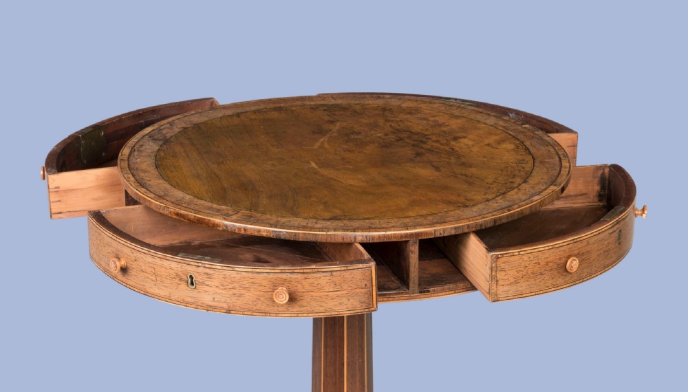 A small Regency mahogany drum table featuring a circular top with frieze drawers, supported on an inlaid central column and four swept legs with brass castors. View V
