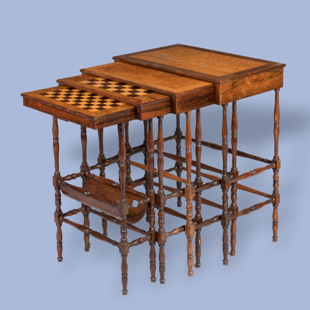 A set of four graduating brown rosewood quartetto tables featuring spindled legs and an inlaid chessboard top nested together.