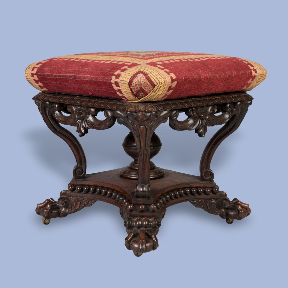 A pair of carved rosewood footstools with patterned red fabric cushions, scrolled supports, and claw feet. View III