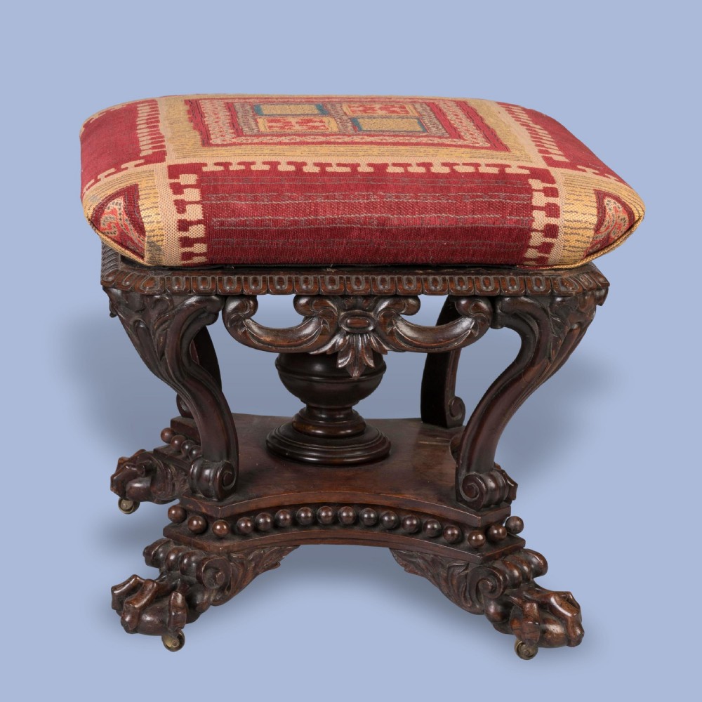 A pair of carved rosewood footstools with patterned red fabric cushions, scrolled supports, and claw feet. View IV