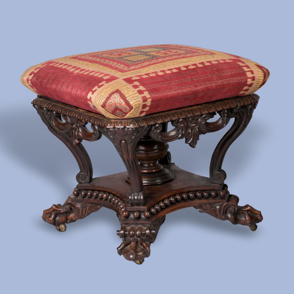 A pair of carved rosewood footstools with patterned red fabric cushions, scrolled supports, and claw feet. View V