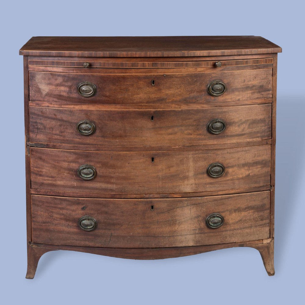 A George III mahogany bowfront chest featuring four graduated drawers with brass oval handles and splayed bracket feet. View II