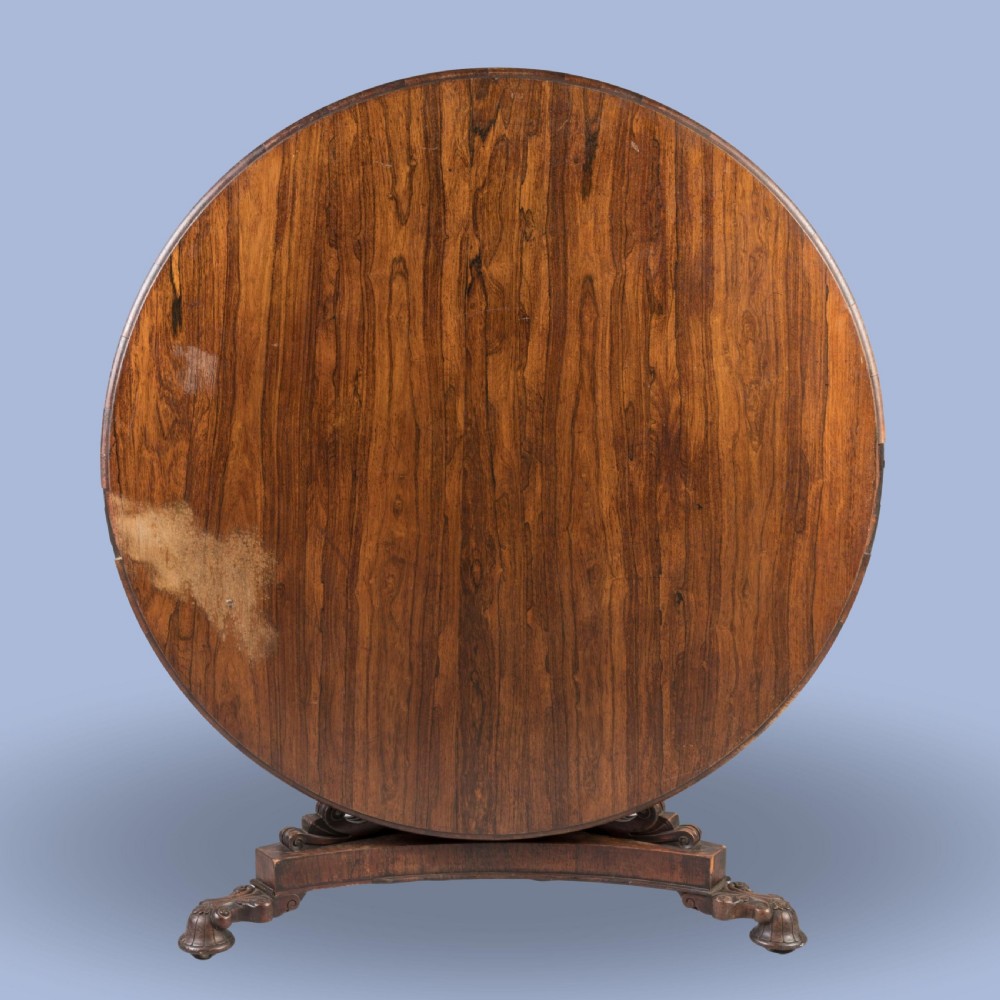A circular 19th-century William IV centre table crafted from dark wood with a carved central pedestal and platform base with scroll feet. View II