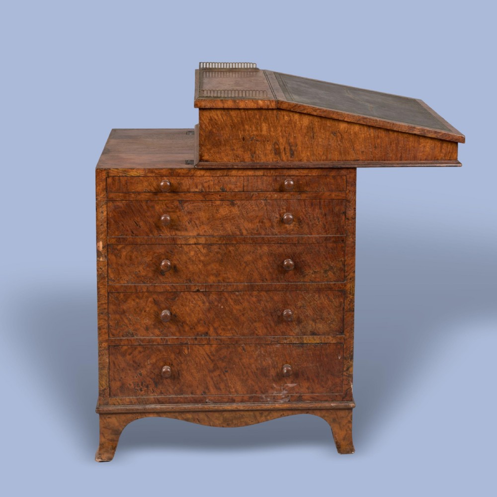 A late Georgian burr elm davenport desk featuring a sliding leather-topped writing slope with a brass gallery above stacked drawers with turned wooden knobs.