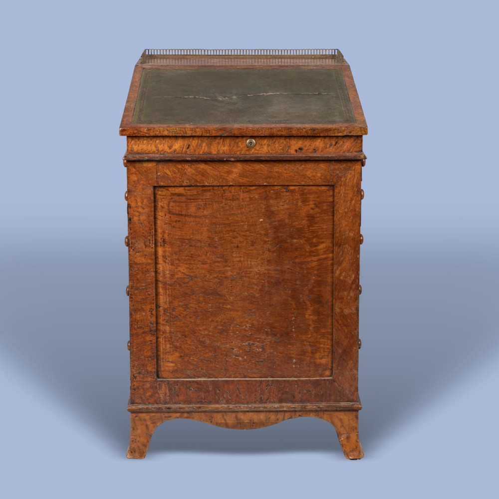 A late Georgian burr elm davenport desk featuring a sliding leather-topped writing slope with a brass gallery above stacked drawers with turned wooden knobs. View V