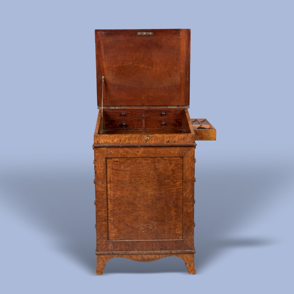 A late Georgian burr elm davenport desk featuring a sliding leather-topped writing slope with a brass gallery above stacked drawers with turned wooden knobs. View VI